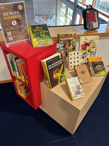 BookCube Bienen Hummeln und Wiesen, Bücher zum Thema präsentiert auf einem quadratischen Holzmöbel mit roten Akzenten. Zu sehende Titel sind z.B. "Die Wildbienen Deutschlands", "Mein Bienengarten" oder "Der Hummelstaat"